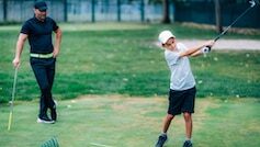 Personal Golf Lessons. Golf Instructor Adjusting Swing of a Young Boy.